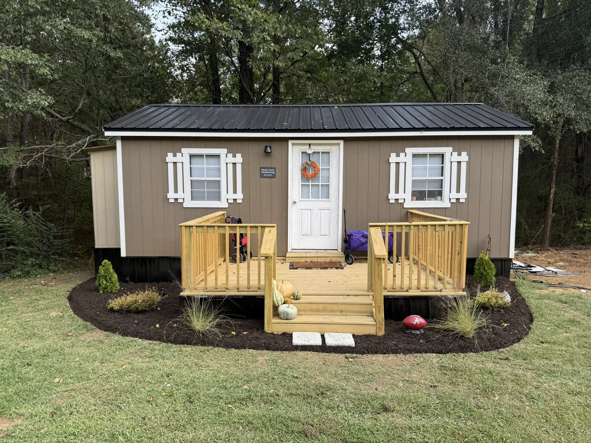 A completed Mommy & Me tiny house at LifeSource with a wooden deck and porch